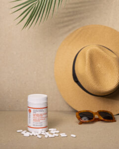 Niacinamide tablets with a hat, sunglasses and palm frond in background